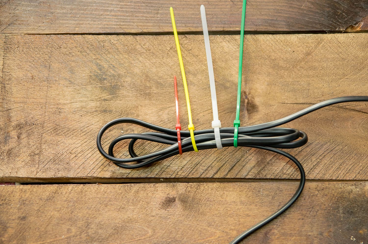 Black cables tied up with four different colored zip ties.